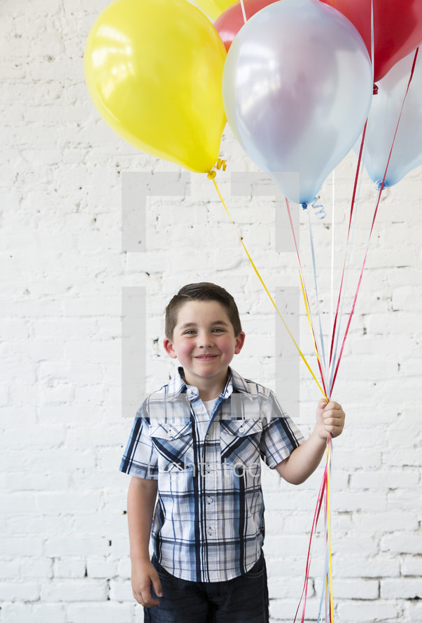 a boy child holding balloons 