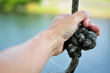 Mans hand grasping a knotted rope