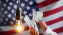 Glowing Edison light bulb on american USA flag background. 