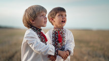 Beautiful portrait of little ukrainian boys singing song in wheat field after harvesting. Children in traditional embroidery vyshyvanka shirt. Ukraine, national costume, happy childhood future