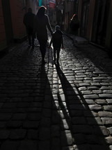mother and son walking on a cobblestone street 