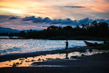 a boy standing on a beach at sunset 
