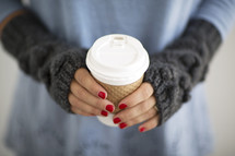 a woman holding a paper coffee cup 