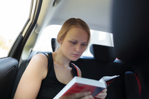 Woman reading a book in the car