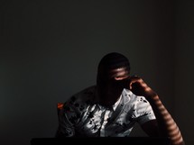 a man sitting in shadows thinking 