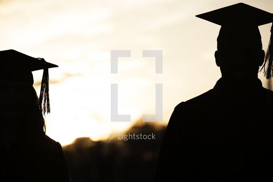 silhouettes of graduates in cap and gown.