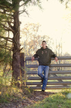 Teen leaning against a farm gate.