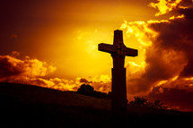 sky on fire and stone cross on a hill 