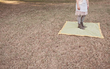 woman standing on a blanket in the grass
