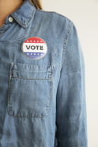 A woman wearing a denim shirt with a "Vote," button.