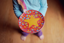 child holding a hand painted plate with a star 