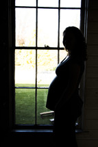 silhouette of a pregnant woman standing in a window 