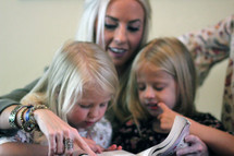 a mother reading to her daughters 