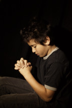 boy with his fingers laced in prayer