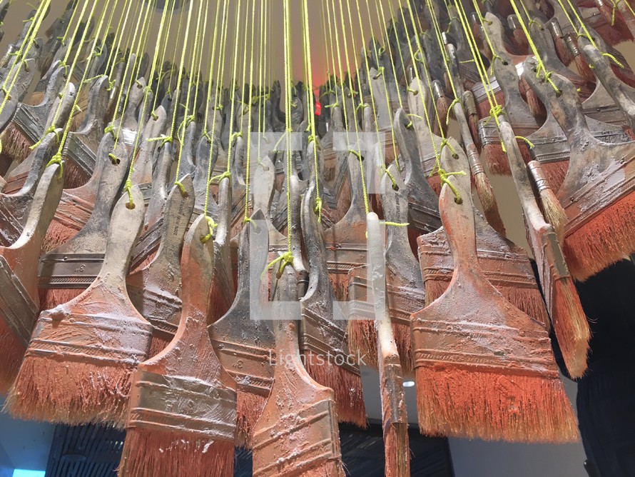 old paint brushes hanging on a string 