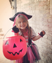 a little girl trick-or-treating dressed as a pirate 
