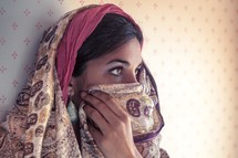 Middle eastern women revealing her eyes and covering the lower part o fher face with her shawl.