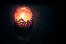 A candle burning in a decorative jar.