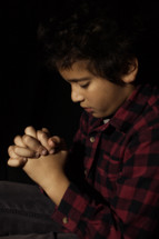 little boy with his fingers laced in prayer to God