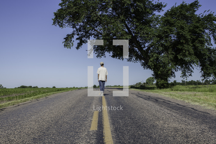 man standing in the middle of a road with his back to the camera 