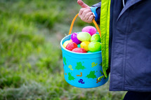 A child holding a basket of colorful Easter eggs.