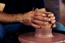 A potter molds clay on a potter's wheel