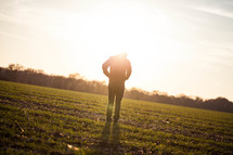 silhouette of a man in a field glowing under sunlight