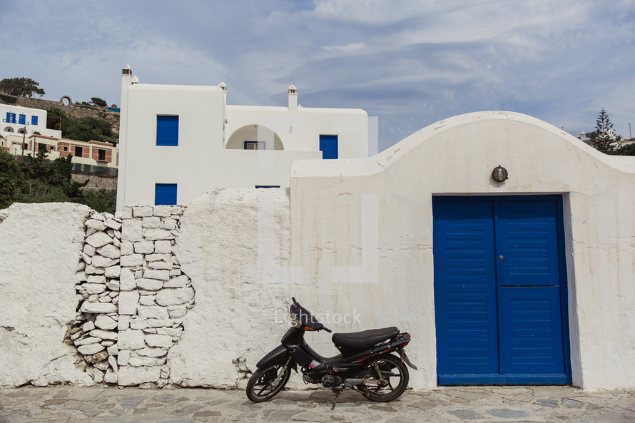 motorcycle parked in front of a white house in Greece white blue doors 