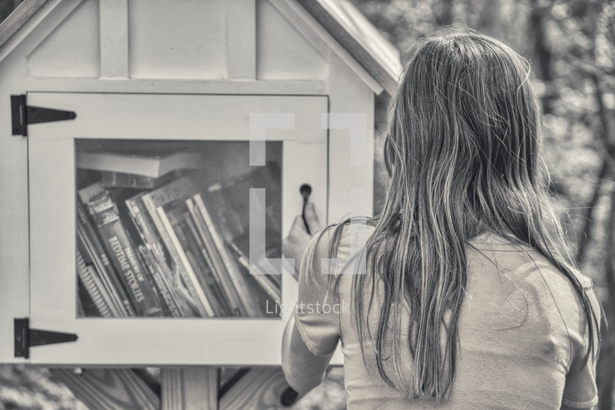girl visiting a little library in a neighborhood 