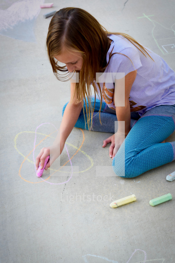 girl drawing an atom in sidewalk chalk 