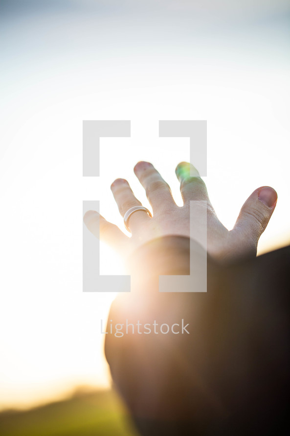 hand reaching out to God glowing in sunlight