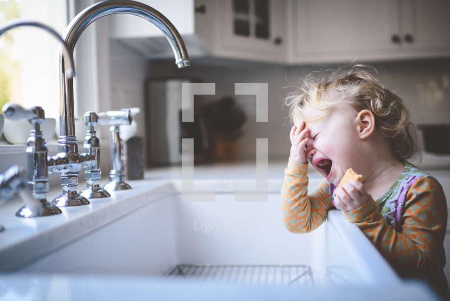 toddler crying by a sink 