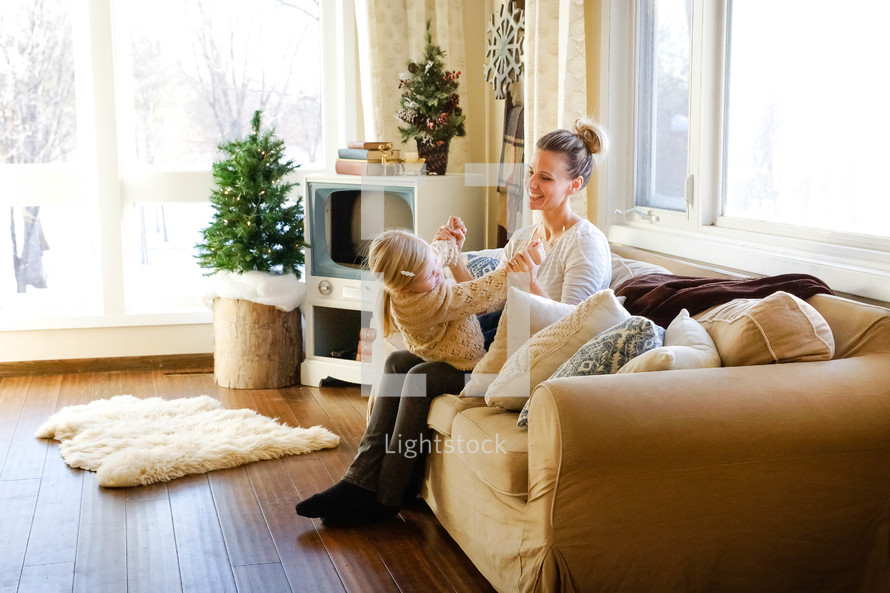 playful mother and child sitting on a couch 