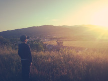 A boy watching the sun set on the horizon.