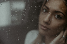 Woman's face through rainy window