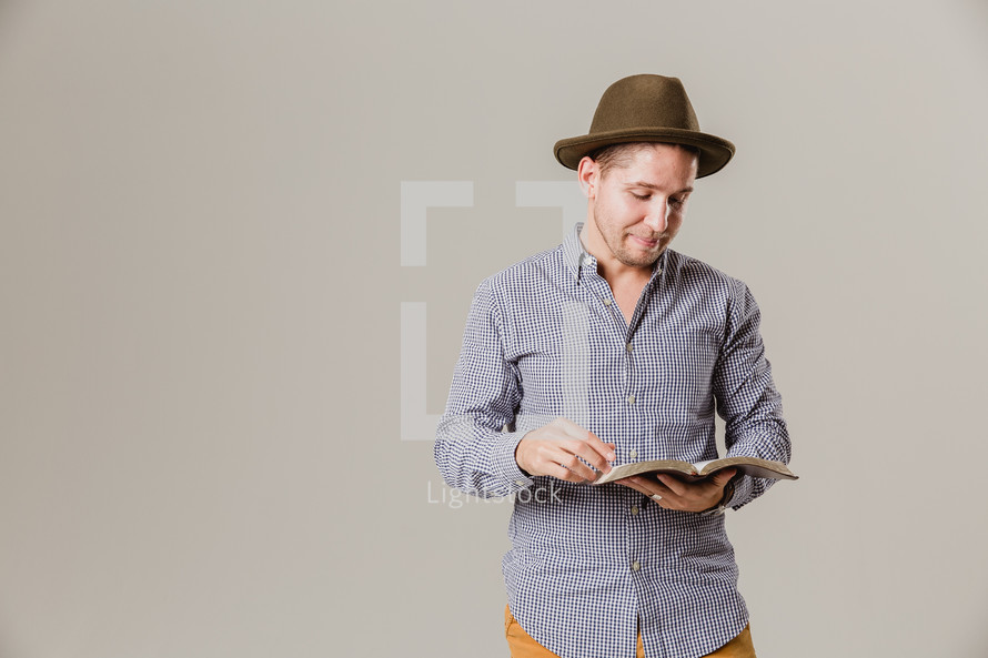 man in a hat reading a Bible 