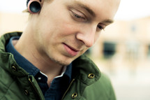 A young man in a green coat with ear lobe plugs.