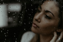 Woman's face behind rainy window