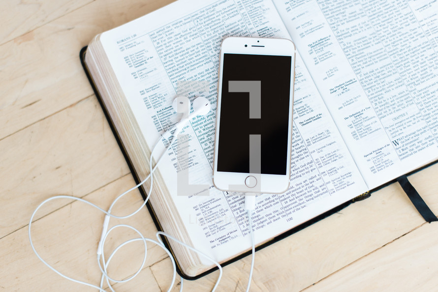 iPhone with earbuds on a Bible 