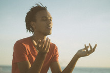 african-american man sitting on a beach meditating 