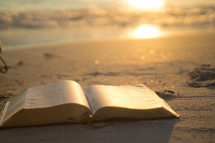 open Bible on a beach at sunrise 