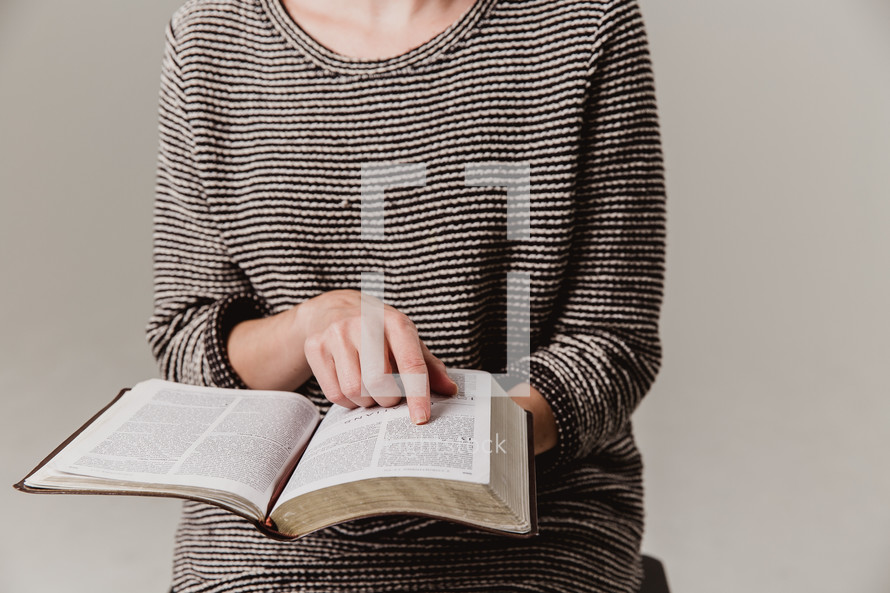 woman sitting on a stool reading a Bible 