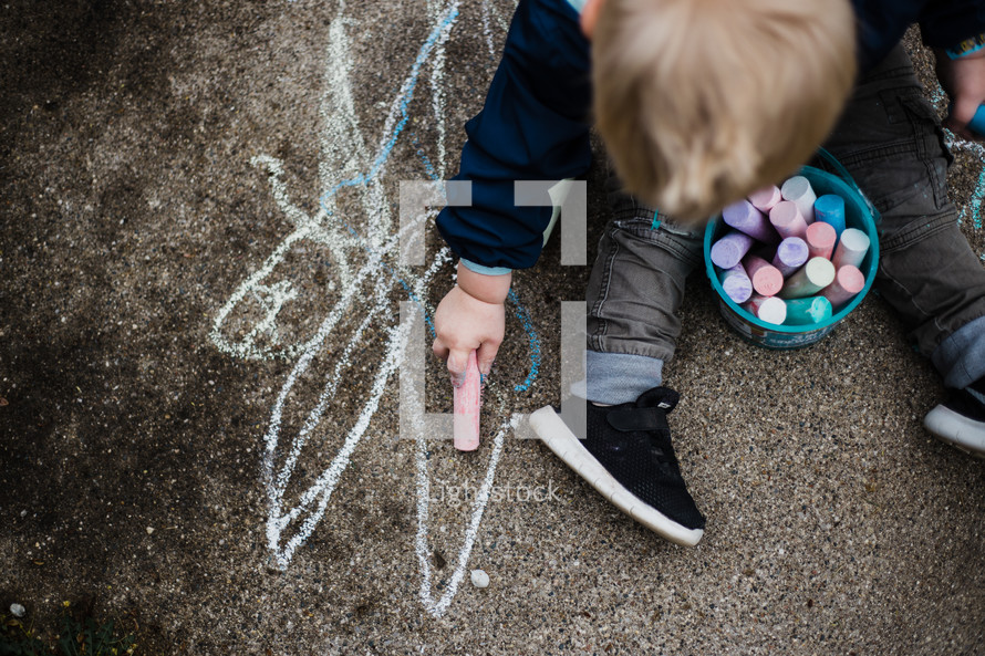 toddler boy coloring with sidewalk chalk 