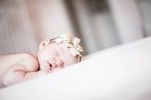 Infant with headband sleeping on tummy in crib.