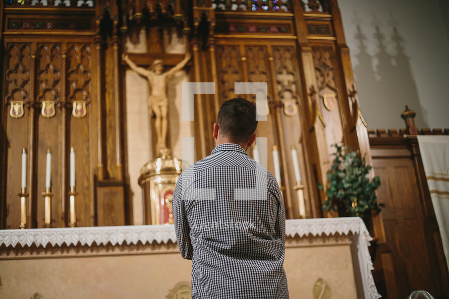 Young man praying in front of tabernacle in Catholic church