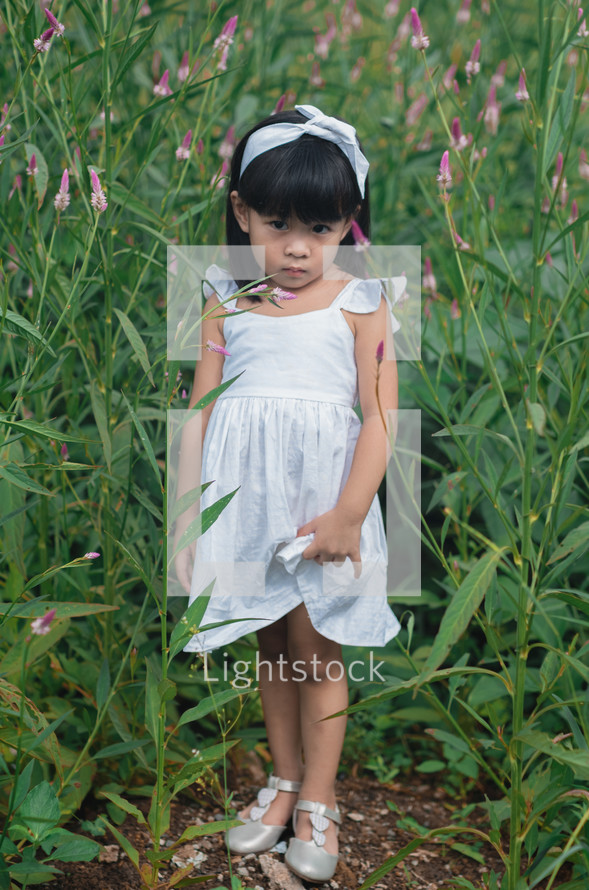 a little girl in a dress standing in a field 