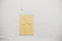 yellow shutters on a white wall 