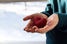 cupped hands with a knit heart 