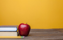 apple, books, and pencil on a teacher's desk 
