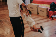 a father swinging her toddler son around 